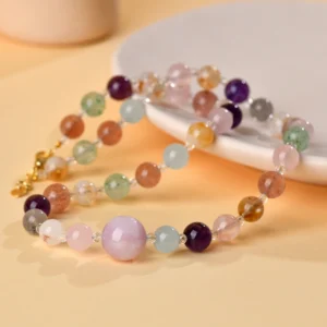 Side angle studio stylized photo natural multi gem rutilated quartz crystal love attraction clavicle necklace laid on white ceramic plate