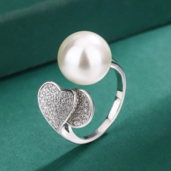Macro close-up shot double heart pave cubic zirconia imitation pearl open adjustable ring, showing heart inlay detail, pearl surface gloss and open band structure