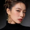 Side profile shot female model wearing hollow four leaf clover geometric long gold drop earrings