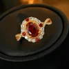 Twisted split shank adjustable ring with oval simulated ruby halo placed inside red lined jewelry box close up photo