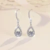 Warm beige background luxury studio photo pair S925 silver moissanite teardrop halo dangle earrings, highlighting moissanite fire sparkle and polished silver luster