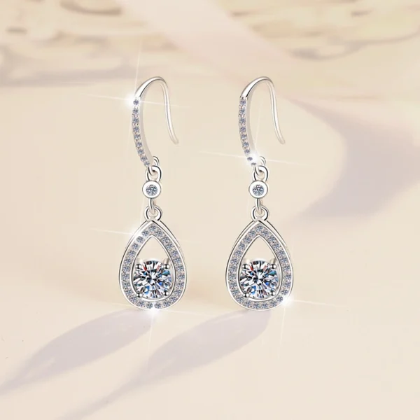 Warm beige background luxury studio photo pair S925 silver moissanite teardrop halo dangle earrings, highlighting moissanite fire sparkle and polished silver luster