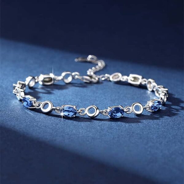 Side view of ocean heart blue crystal bracelet showing the adjustable chain and crystal details on blue background