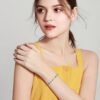 Model wearing ocean heart blue crystal silver plated bracelet with yellow top, lifestyle shot Title: Ocean Heart Bracelet Lifestyle Worn View
