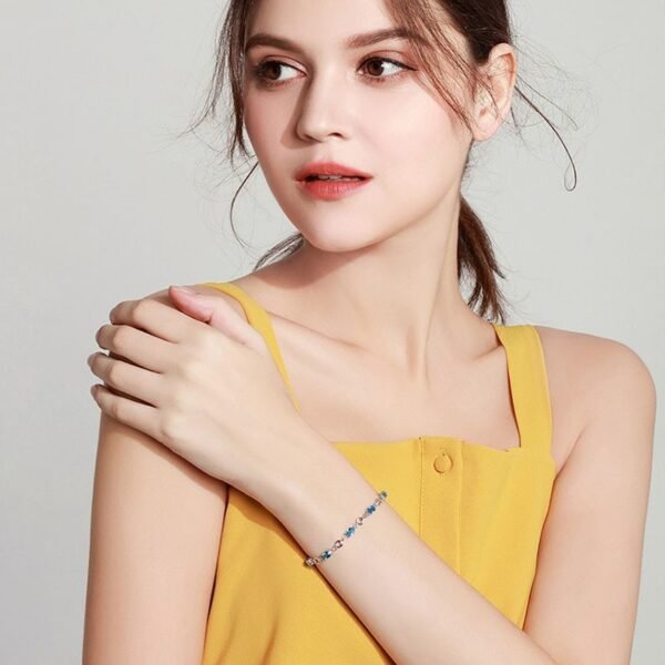 Model wearing ocean heart blue crystal silver plated bracelet with yellow top, lifestyle shot Title: Ocean Heart Bracelet Lifestyle Worn View