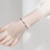 Close-up of ocean heart blue crystal bracelet worn on a woman’s wrist with lace sleeve background