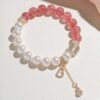 Flat lay view of strawberry quartz bracelet with size details (9-10mm quartz, 10mm pearl, 12mm crystal) on light background