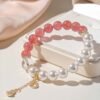 Strawberry quartz and pearl bracelet displayed with light silk fabric and gift box, elegant aesthetic shot