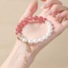 Delicate strawberry quartz and imitation pearl bracelet with gourd pendant held in a hand