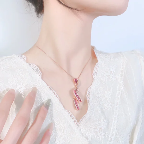 Close up shot of model neck wearing simulated ruby twist ribbon rose gold pendant necklace