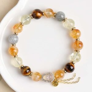 Top-down flat lay of yellow rutilated quartz bracelet with mixed natural gemstones placed on white ceramic plate