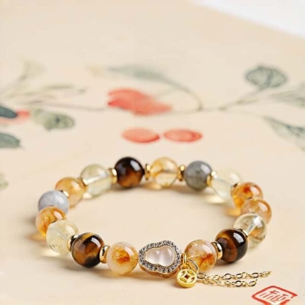 Natural yellow rutilated quartz bracelet with tiger eye citrine and Chinese gourd coin charm on floral background